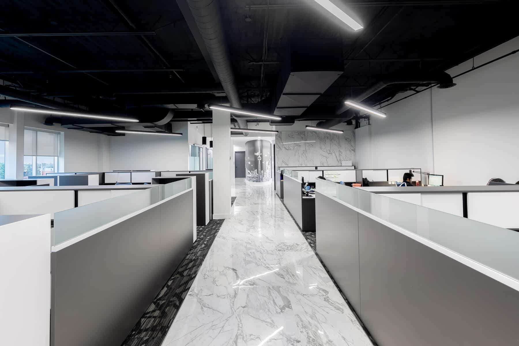 Int&eacute;rieur de bureau moderne avec une d&eacute;coration en noir et blanc, comprenant des bureaux avec s&eacute;parateurs de cabines, des sols en marbre et des plafonniers.